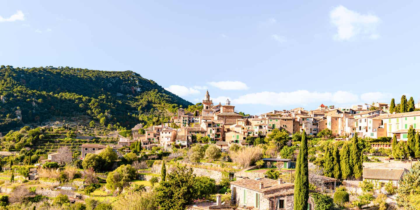 Blick auf Valdemossa auf Mallorca, ein Bergort an grünen Hängen mit blauem Himmel