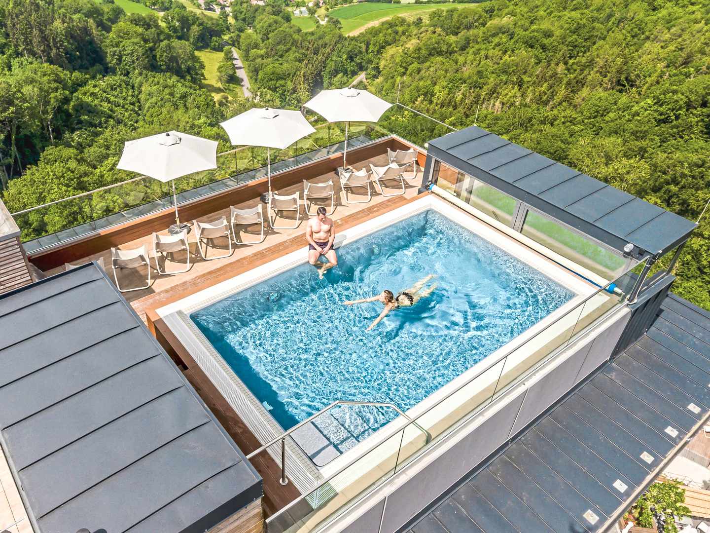 Dachterrassen-Pool mit weitem Blick ins Grüne – kombiniert ruhige Rückzugsbereiche mit kurzer Distanz zum Spa Dachpool im Mawell Resort Langenburg mit Liegen und Blick über die bewaldete Hügellandschaft