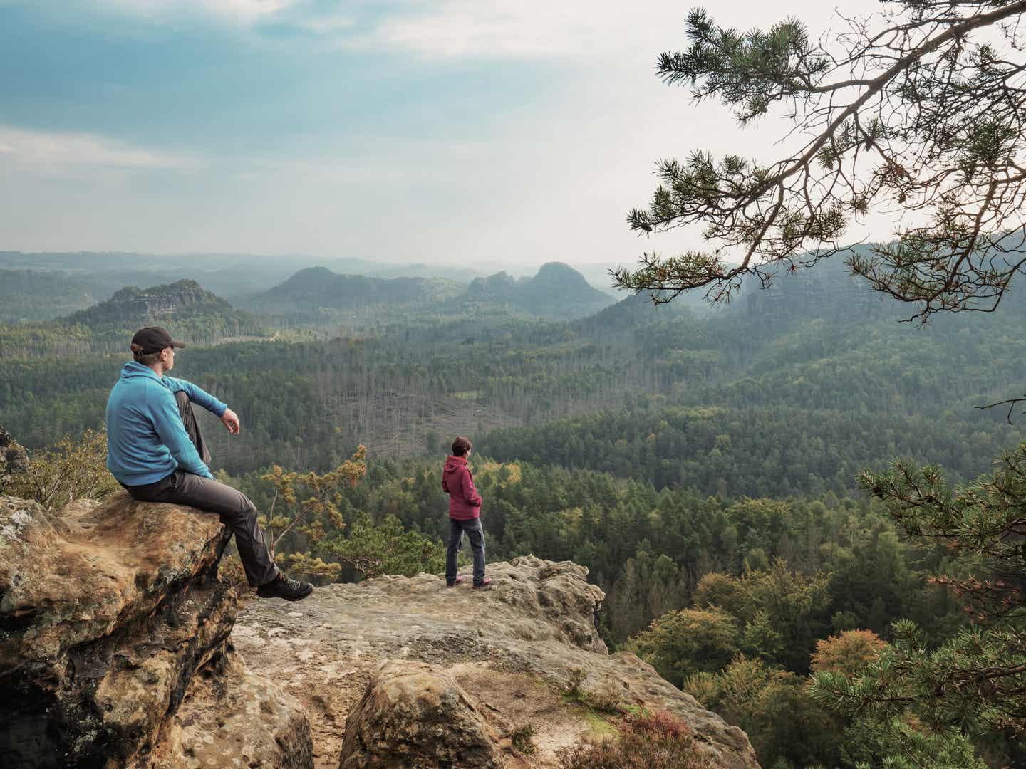 Urlaub in Sachsen mit DERTOUR. Paar genießt bei einer Wanderung den Ausblick von Felsen in der Sächsischen Schweiz