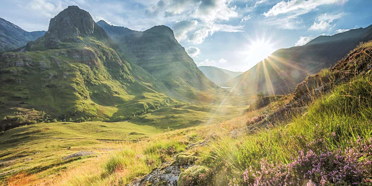 Blick auf die schottischen Highlands mit der Sonne über den Bergen