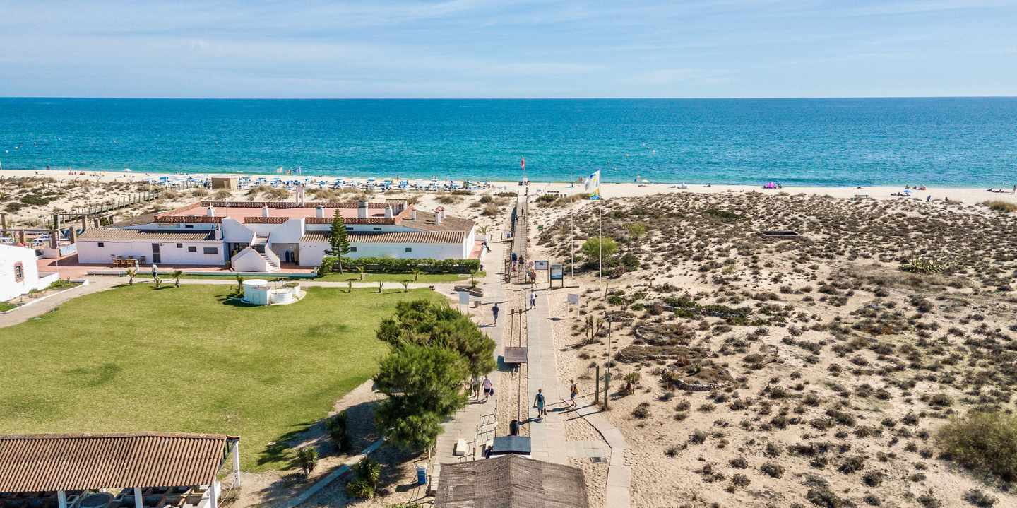 Praia do Barril auf der Ilha de Tavira an der Algarve – Eisenbahn im Vordergrund, Ankerfriedhof und Sandstrand im Hintergrund 