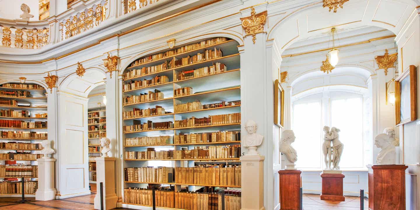 Weiß-goldene Wände und Decken in einer prunkvollen Bibliothek mit vielen Büchern
