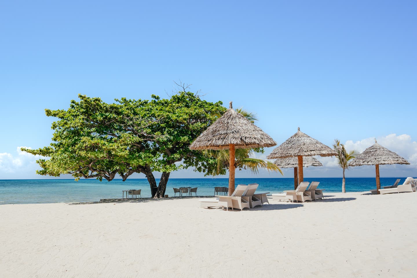 Sonnenliegen und Restauranttische direkt am Meer