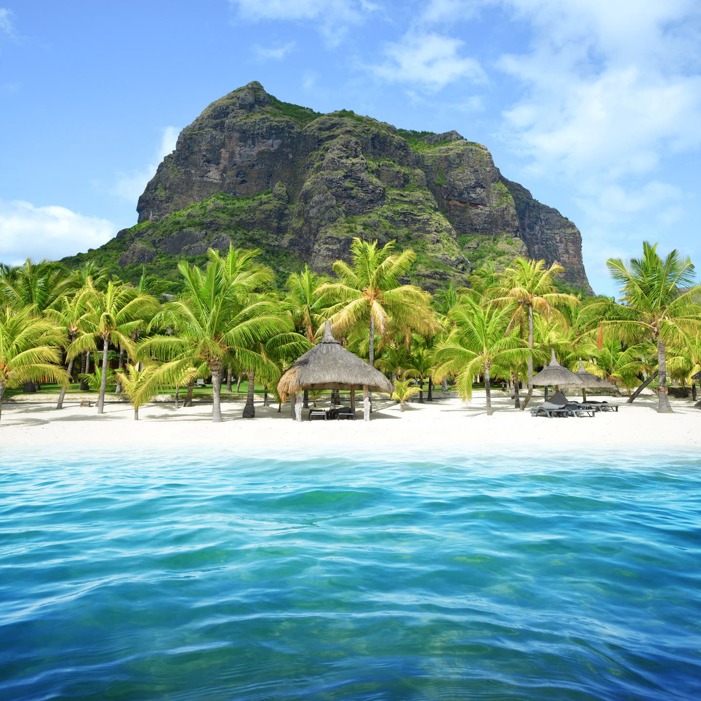 Sandstrand mit Palmen und Blick auf den Le-Morne-Brabant-Berg auf Mauritius, umgeben von blauem Himmel und klarem Wasser