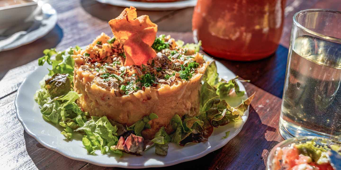 Typisches Gericht in einem Guachinche auf Teneriffa mit Süßkartoffelsalat, Kräutern und lokalem Wein auf Holztisch