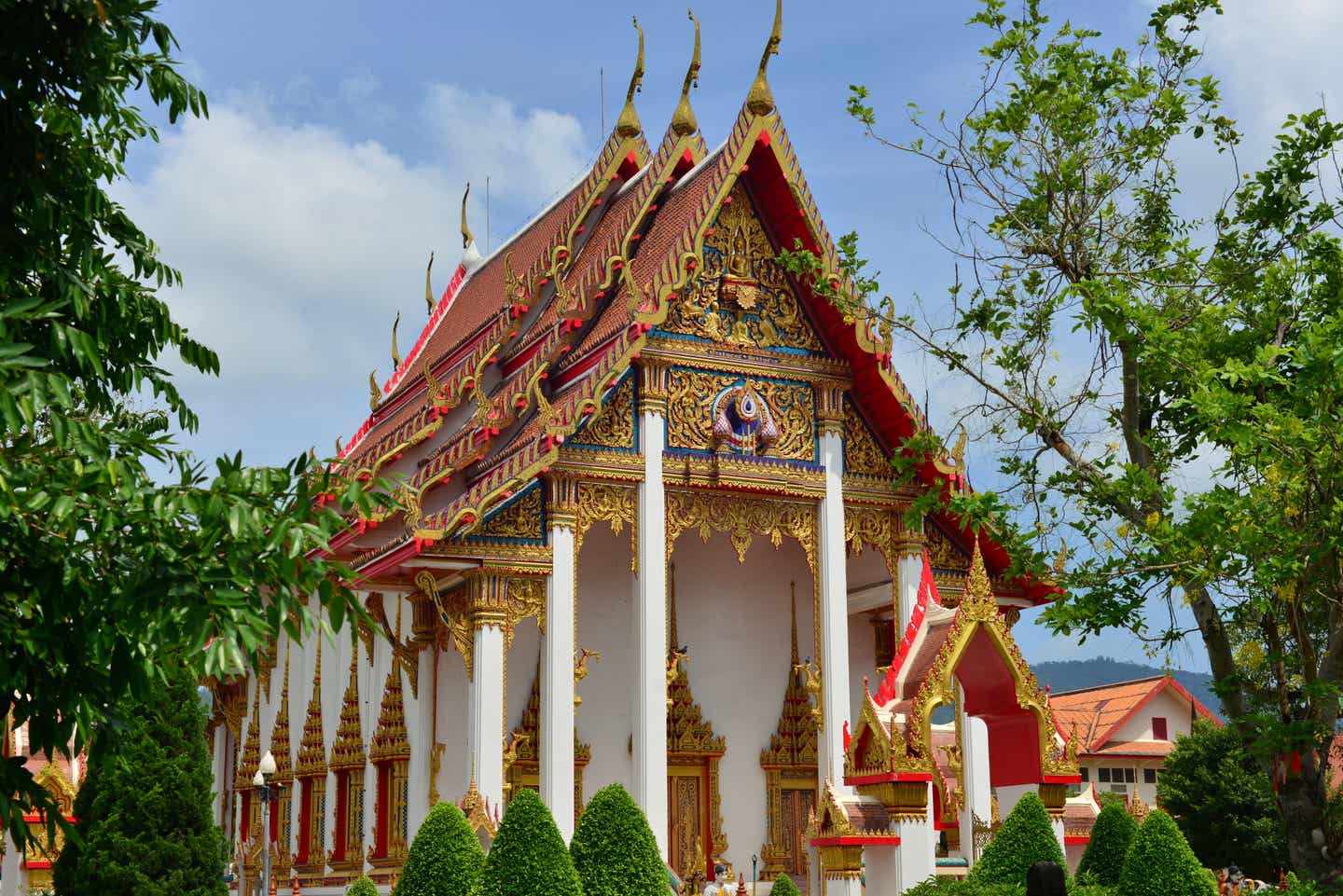 Der Wat Chalong Tempel – ein reich verziertes Bauwerk mit rotem Spitzdach und kalkweißen Wänden