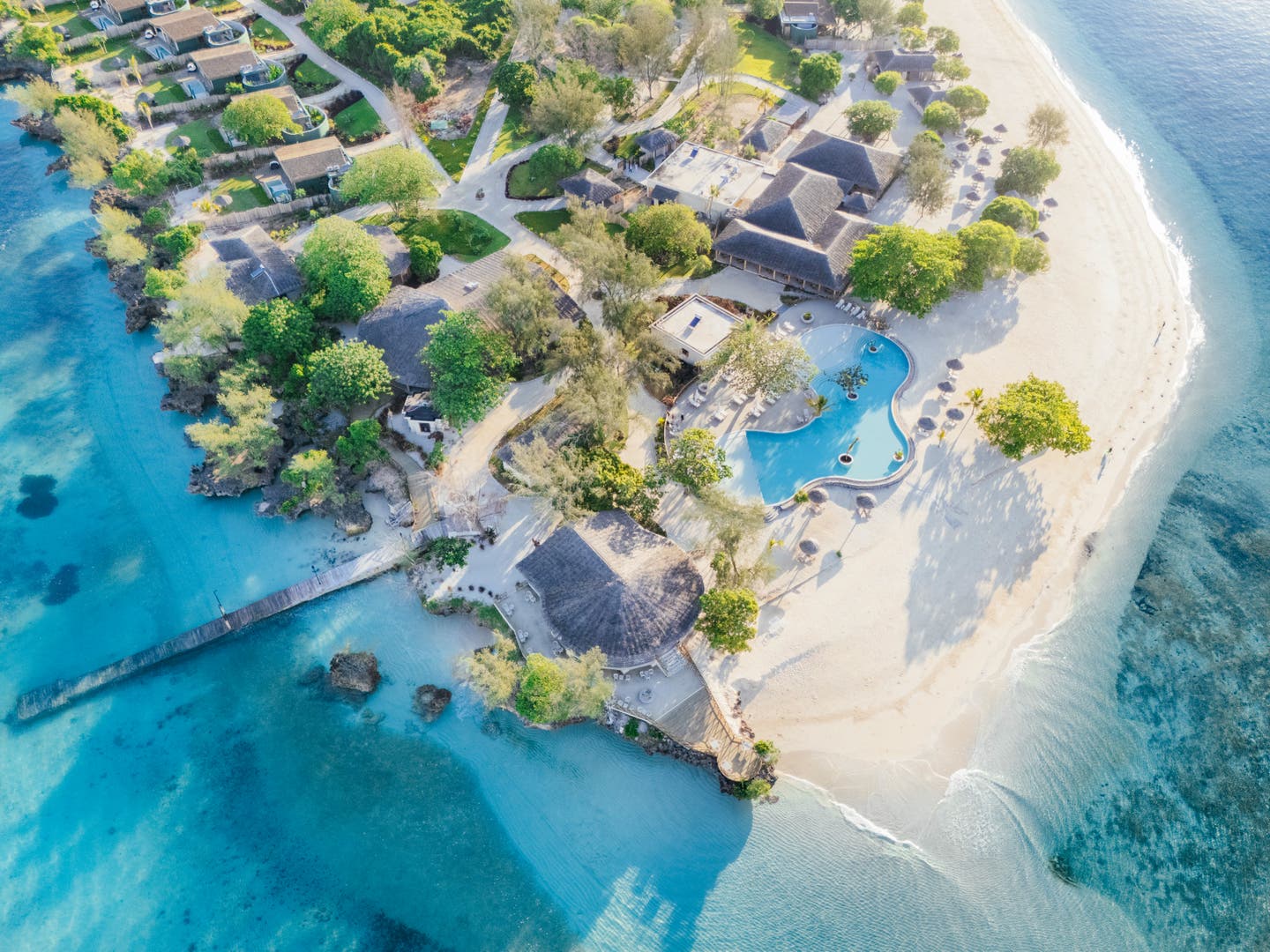Luftbild des Resorts mit Häusern, Pool und Strand
