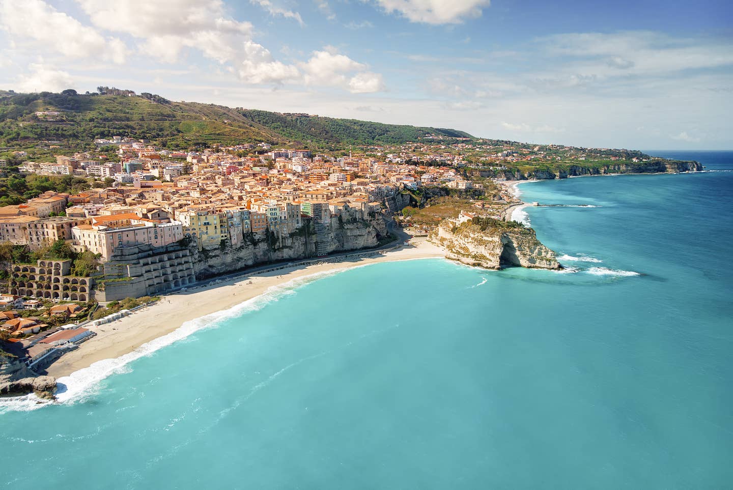 Kalabrien Urlaub mit DERTOUR. Luftaufnahme der Stadt Tropea vom Meer aus mit Strand und den typischen auf steilen Felsen errichteten Häusern