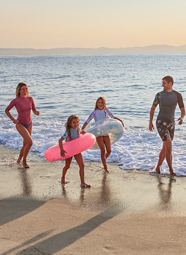 Familienurlaub Familie rennt am Strand im Familienurlaub