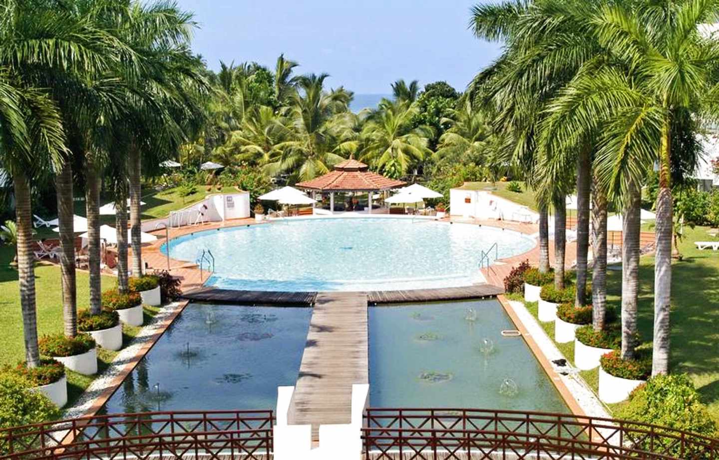 Von Palmen umsäumter runder Pool des Lanka Princess Hotels, auf den ein Steg zuläuft