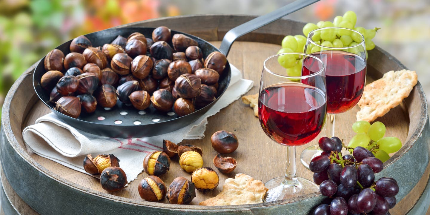 Typischeer Anblick beim Törggelen: ein Holzbrett mit gerösteten Kastanien und rotem Wein
