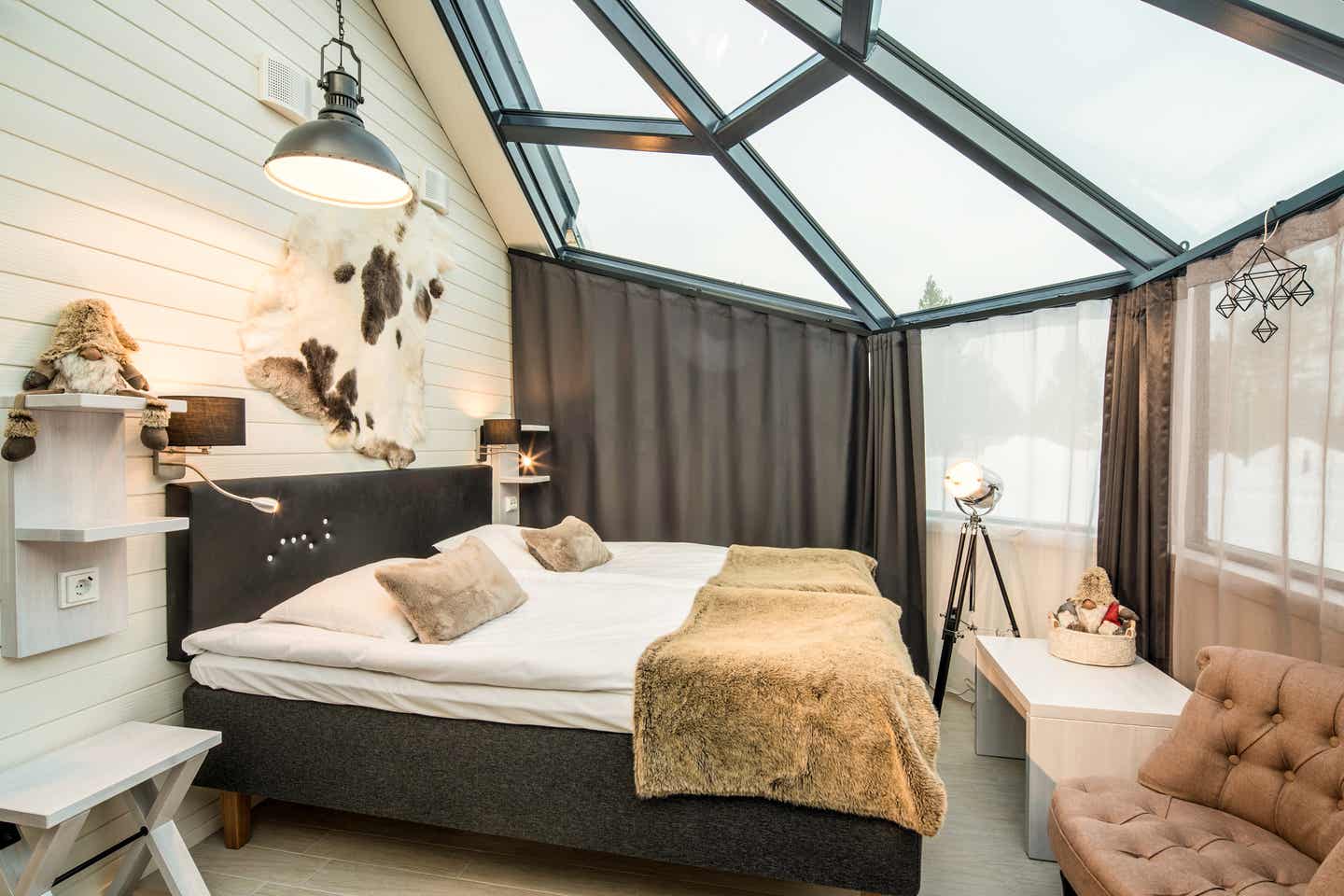Bett mit weichen Decken unter Glasdach des Iglus, Schneelandschaft