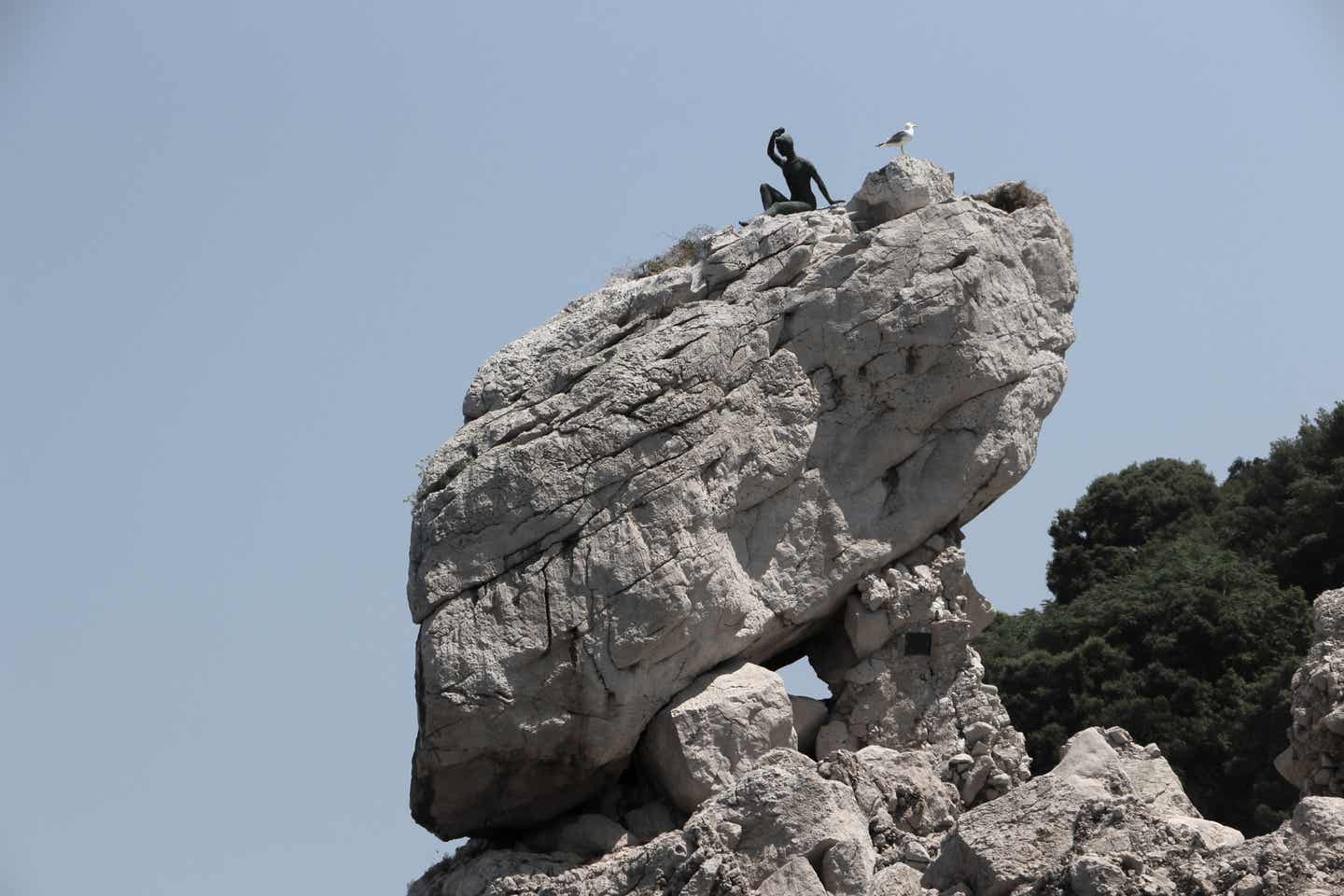 Capri Urlaub mit DERTOUR. Statue des grüßenden Jungen auf einem Felsen der Insel Capri