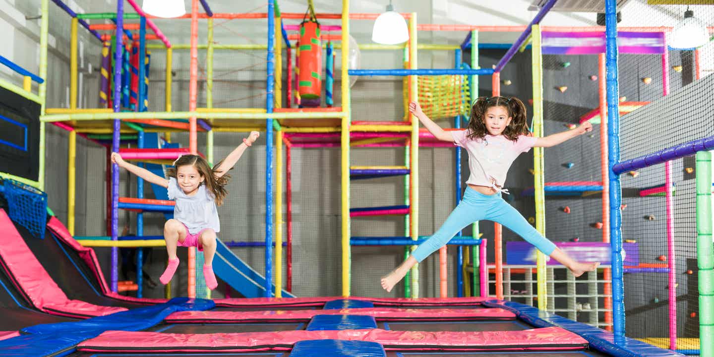 Zwei Mädchen springen auf einer Trampolinlandschaft in einem Indoorspielplatz