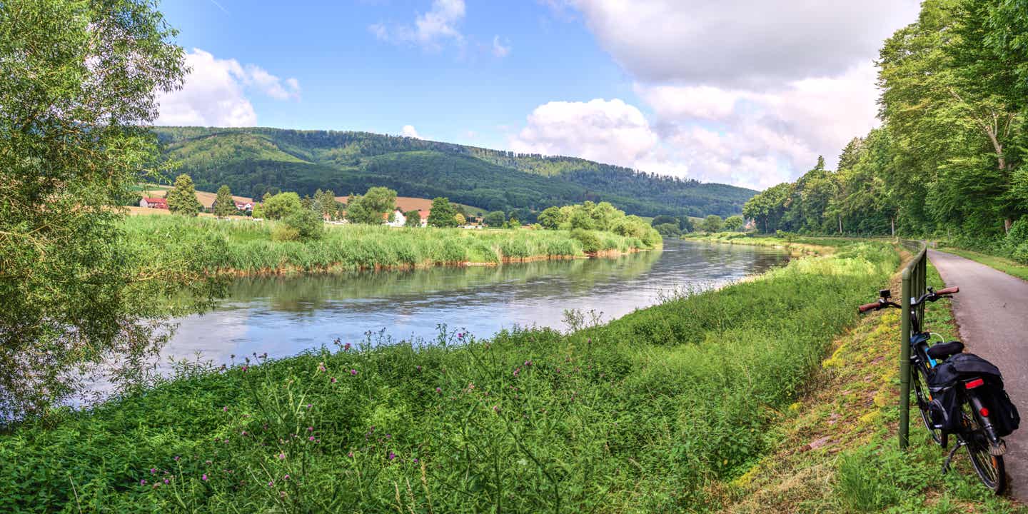 Blick auf die durchs Weserbergland fließende Weser, am rechten Rand steht ein Fahrrad
