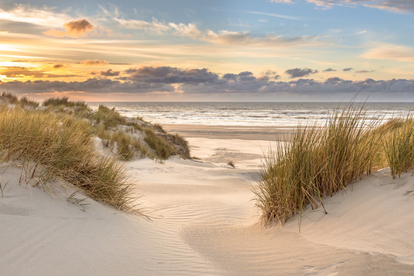 Dünenlandschaft an einem der schönsten Nordsee-Strände bei Sonnenuntergang, mit Blick auf das Meer und einem farbenprächtigen Himmel