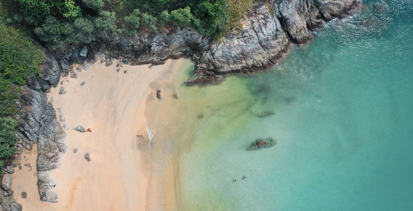 Thailändischer Traumstrand mit türkisblauem Wasser und Felsen aus der Vogelperspektive