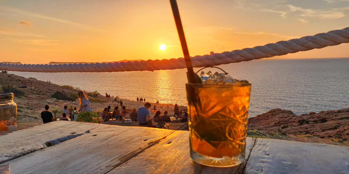 Drink im Sonnenuntergang auf Ibiza mit Blick aufs Meer – typisches Motiv für Ibiza Sunset Bar
