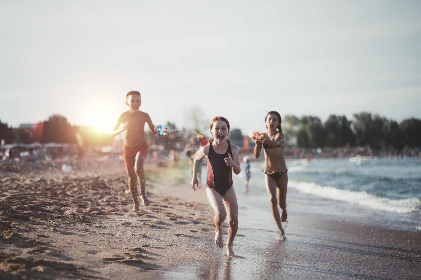 Bulgarien Urlaub mit DERTOUR. Drei Kinder mit Wasserpistolen spielen am Strand