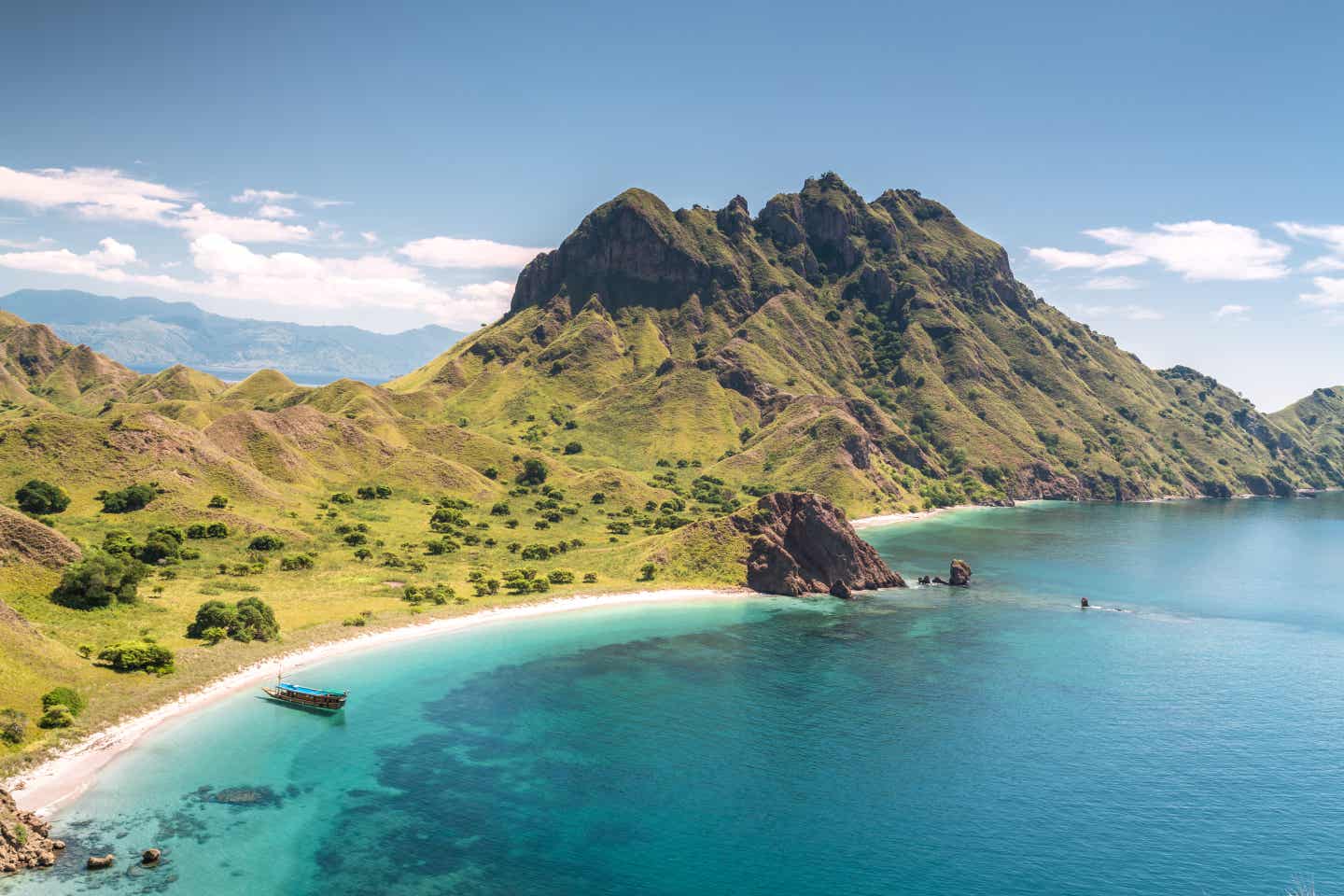 Blick auf die Insel Flores in Indonesien, hohe bewachsene Berge hinter Strand