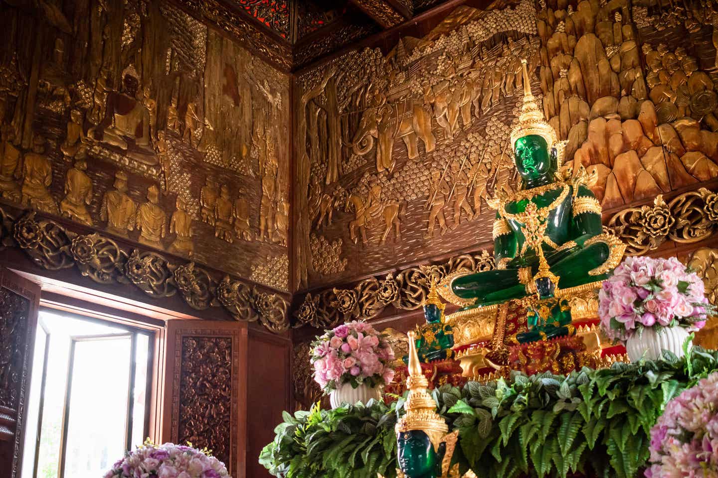 Der Smaragd-Buddha neben bunten Blumen in Bangkoks Königspalast