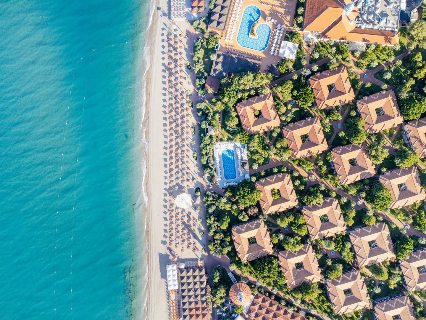 Topshot einer Drohne auf Hotelanlage, Pool und Strand