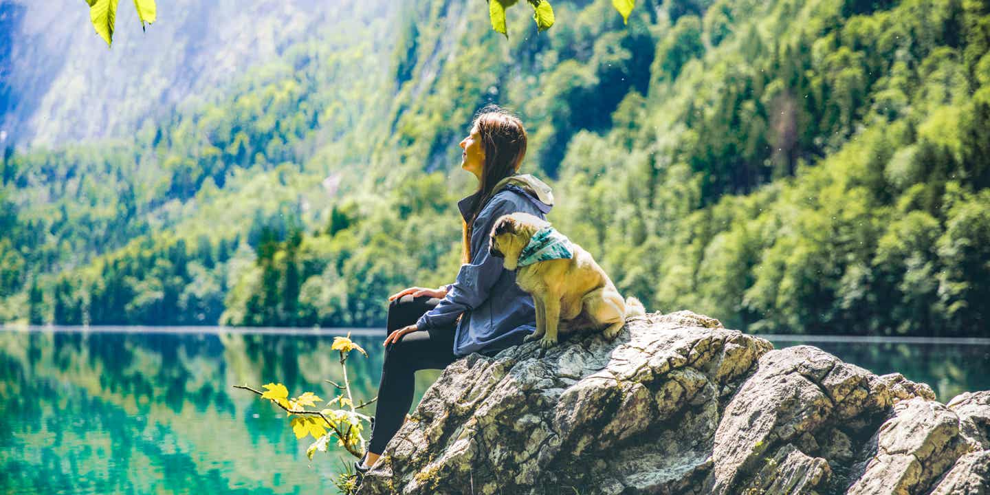 Frauchen im Urlaub mit Hund an einem See in den Bergen
