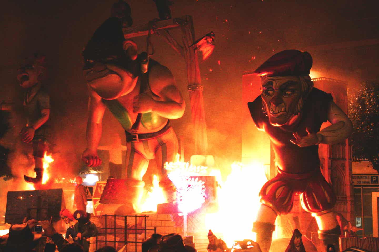 Große Holzfiguren, dazwischen Feuer