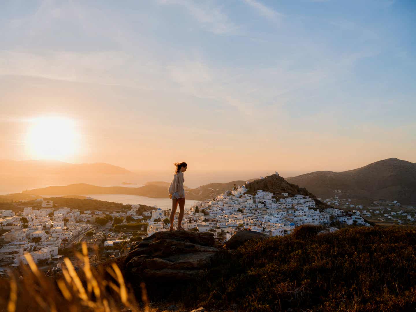 Frau steht auf einer Klippe am Meer beim Sonnenuntergang auf Santorini