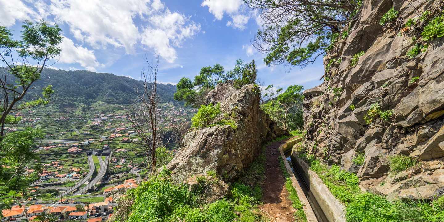 Levada-Wanderweg auf Madeira entlang eines Felswegs mit Kanal und Blick ins grüne Tal