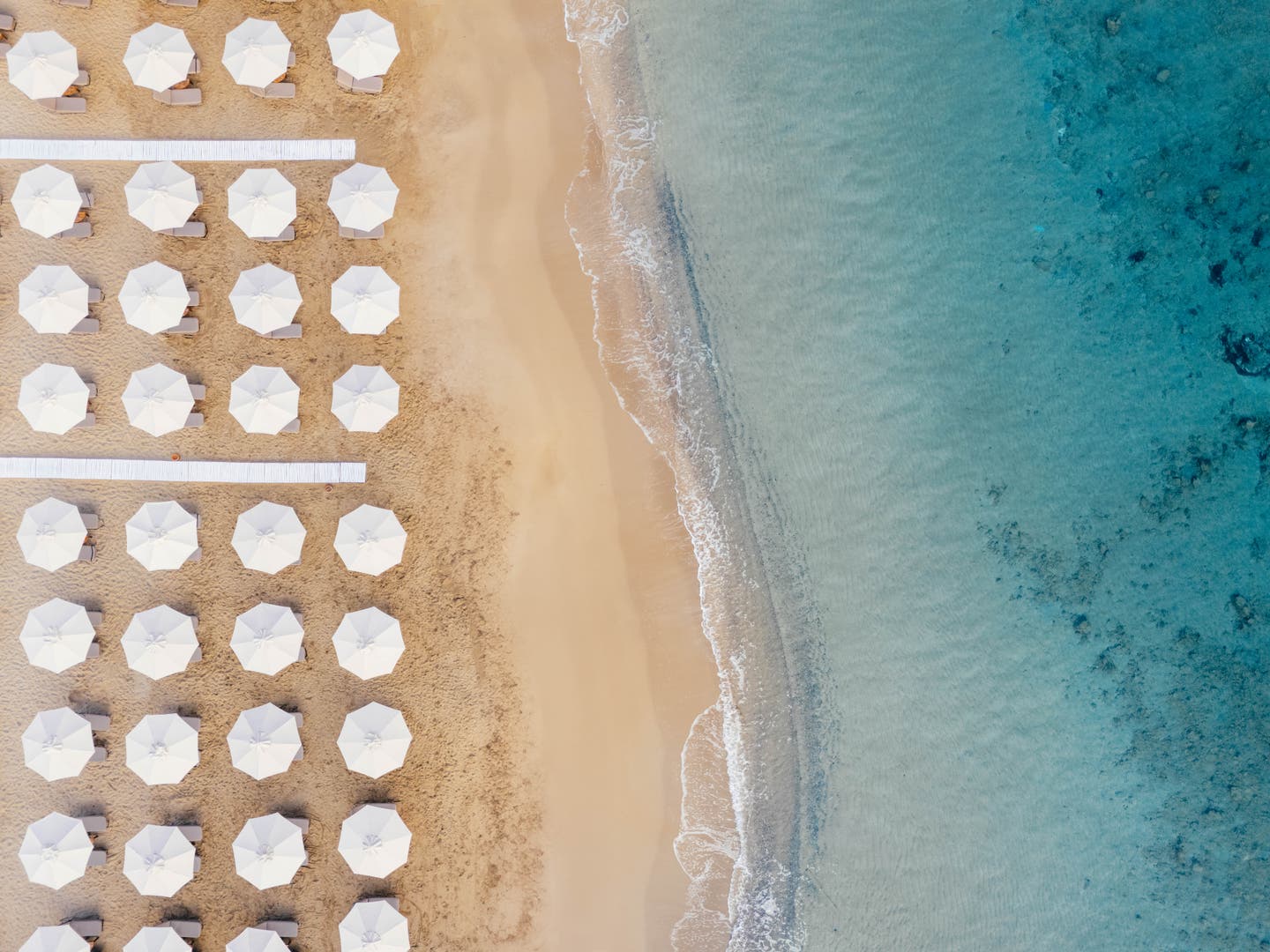 Topshot über den Strand mit weißen Sonnenschirmen