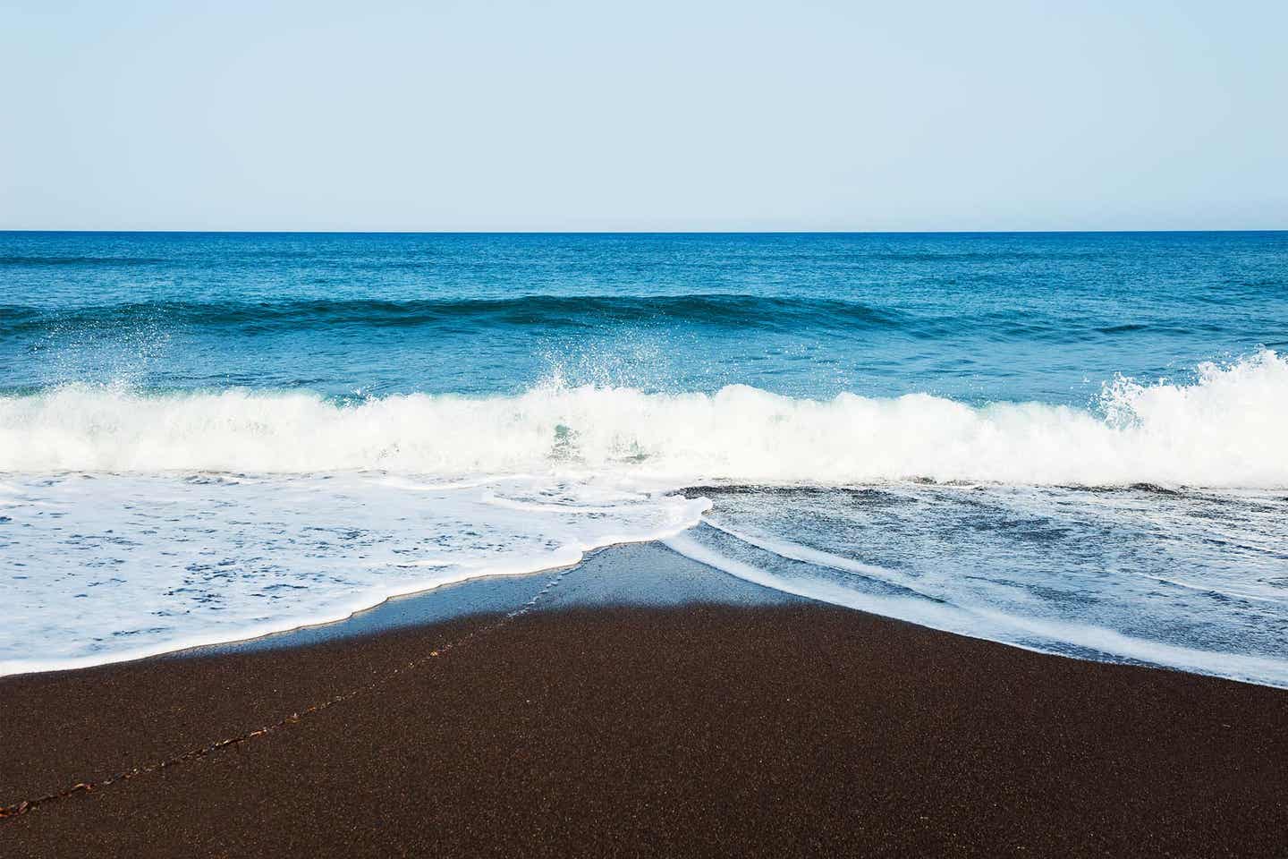 Schwarzer Strand mit blauen Wellen auf Santorini