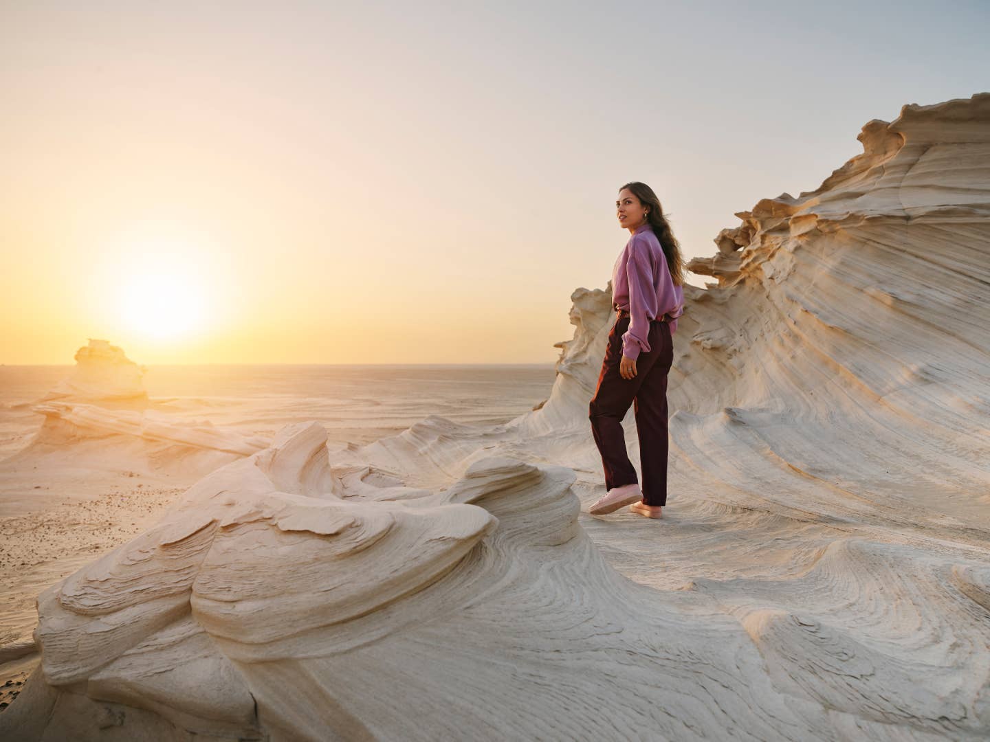 Frau in Wüstenlandschaft bei Sonnenaufgang in Abu Dhabi