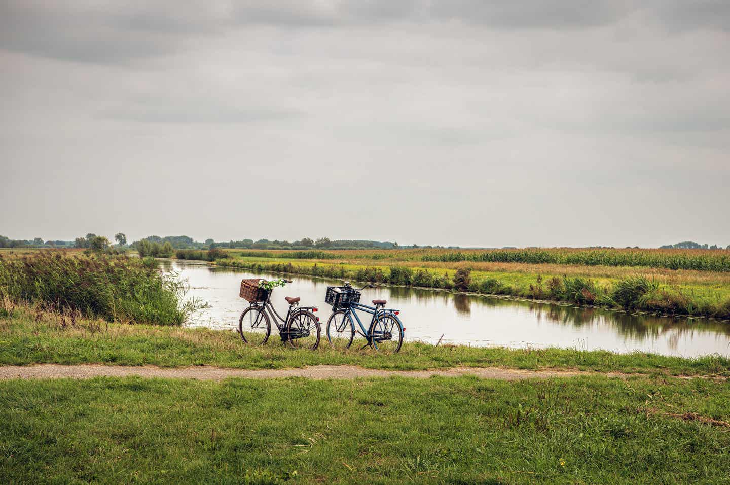 Niederlande Urlaub mit DERTOUR. Zwei Fahrräder parken an einem Flussufer