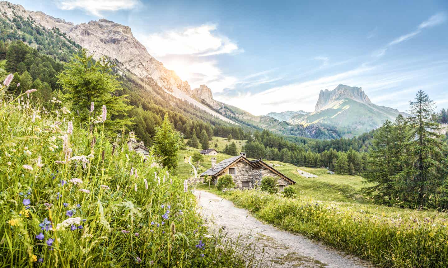 Südtirol Urlaub mit DERTOUR. Berglandschaft in Südtirol mit kleinen Berghütten an einem Weg