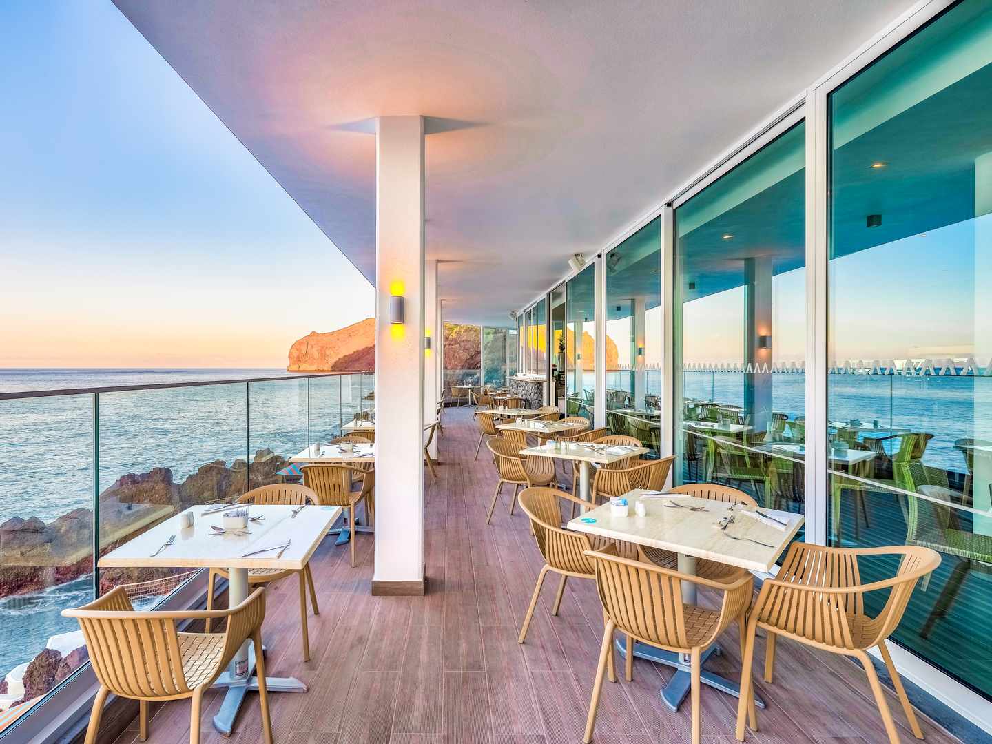 Restaurantterrasse im Sentido Galomar auf Madeira mit gedeckten Tischen, Glasfassade und freiem Blick auf den Atlantik