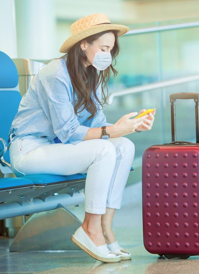 Mehr Informationen Frau mit Maske und Koffer am Flughafen