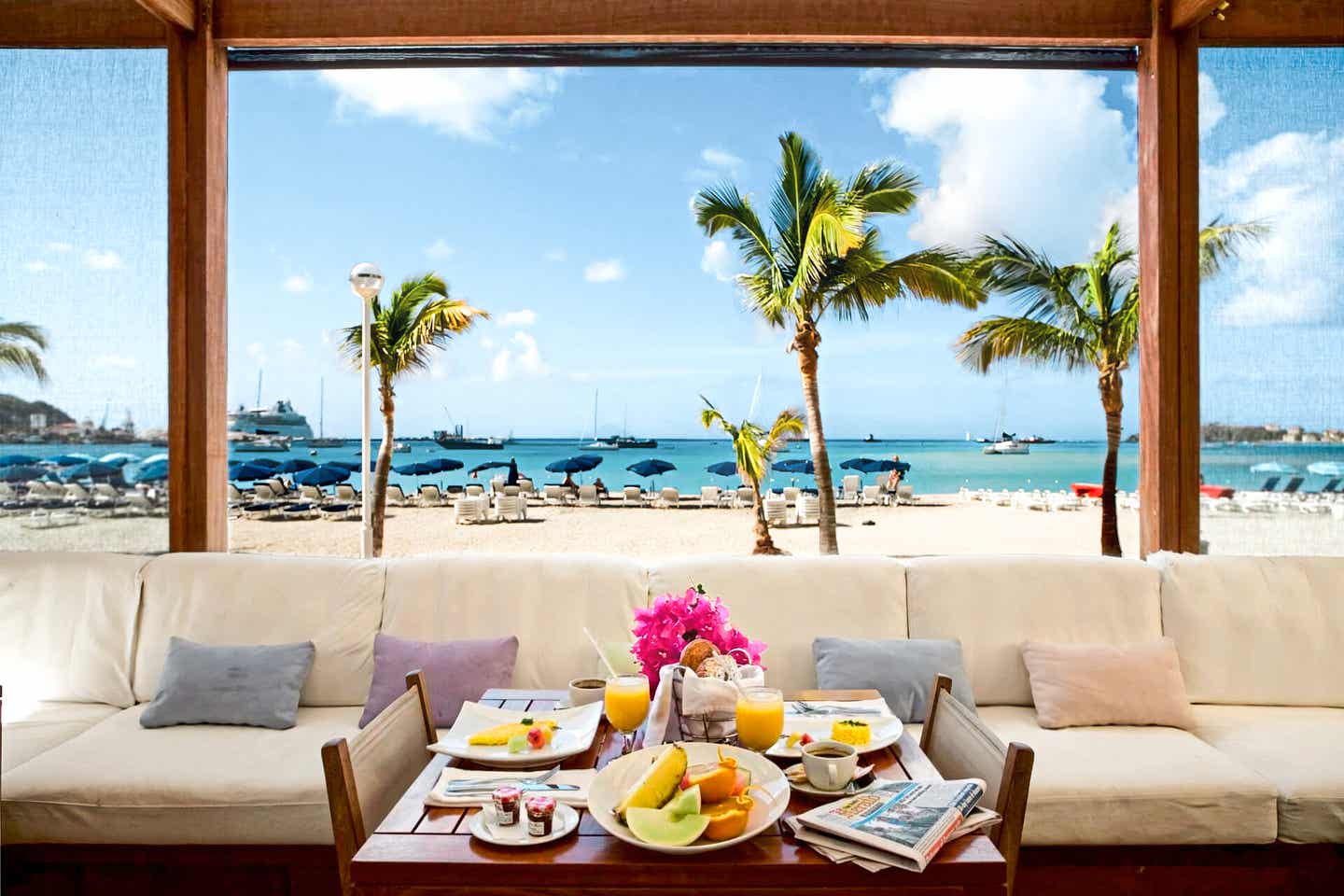 Gedeckter Tisch mit Palmen und Strand im Hintergrund