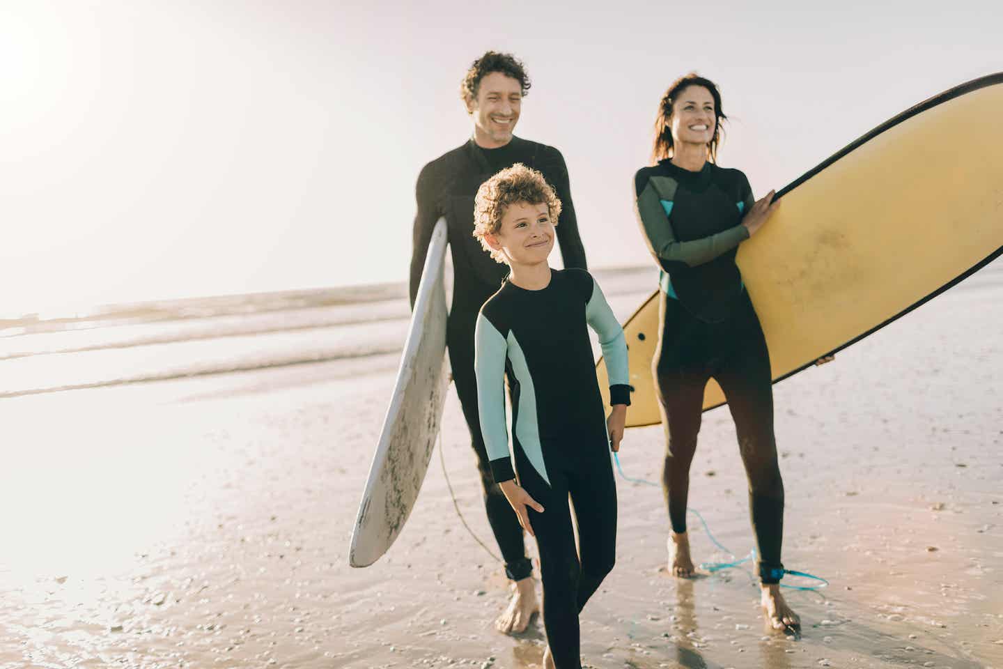 Familie am Strand mit Surfbrettern