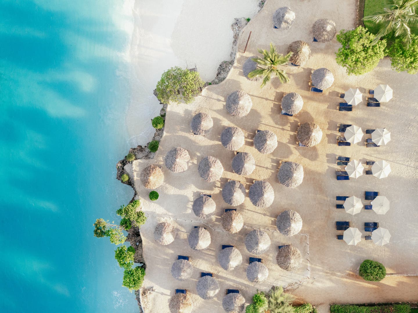 Luftbild des Hotelstrandes mit Sonnenschirmen und -liegen