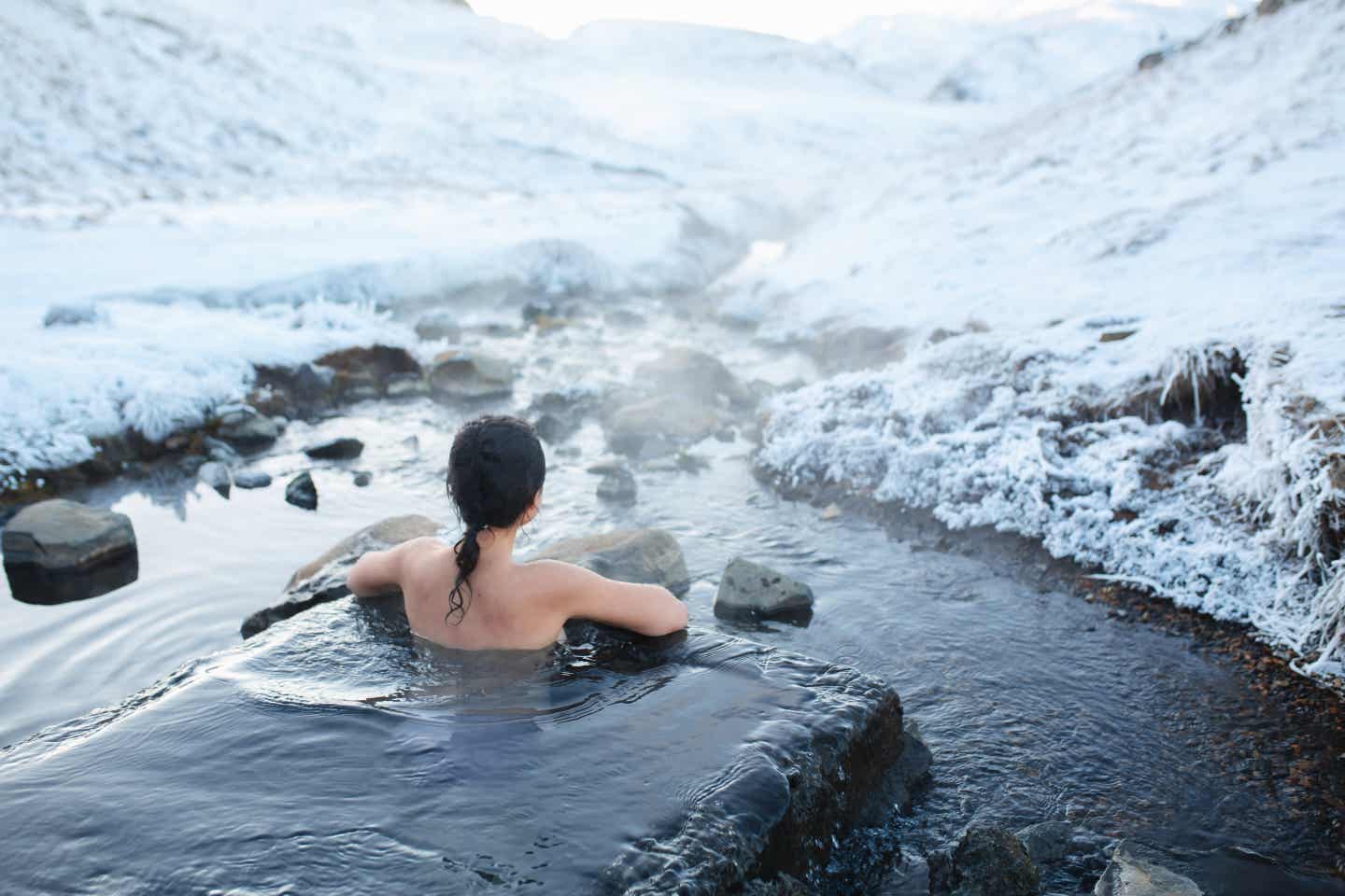 Allein reisen als Frau: baden in heißer Quelle vor schneebedeckter Landschaft