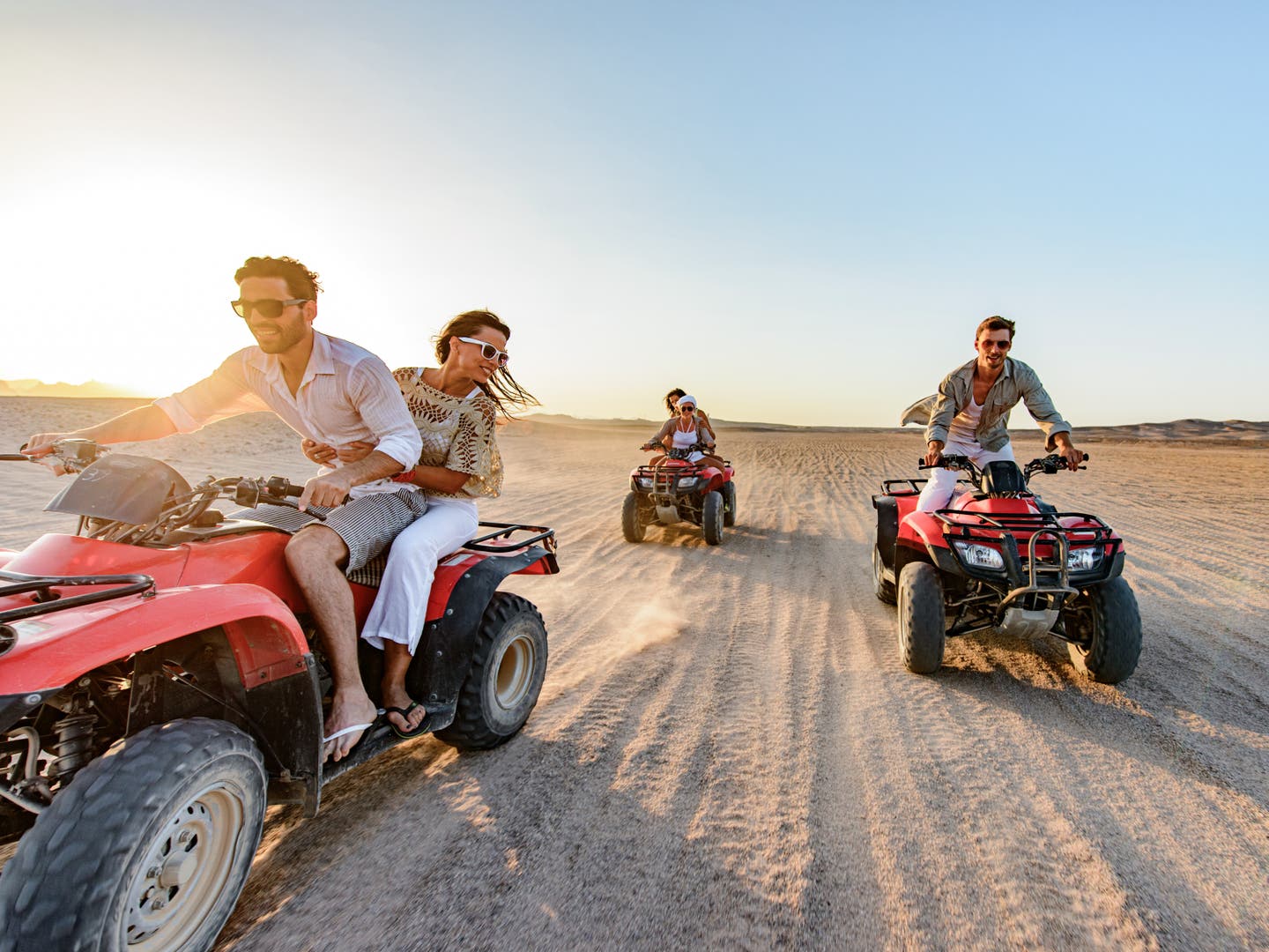 Paare fahren auf dem Quad durch die Wüste