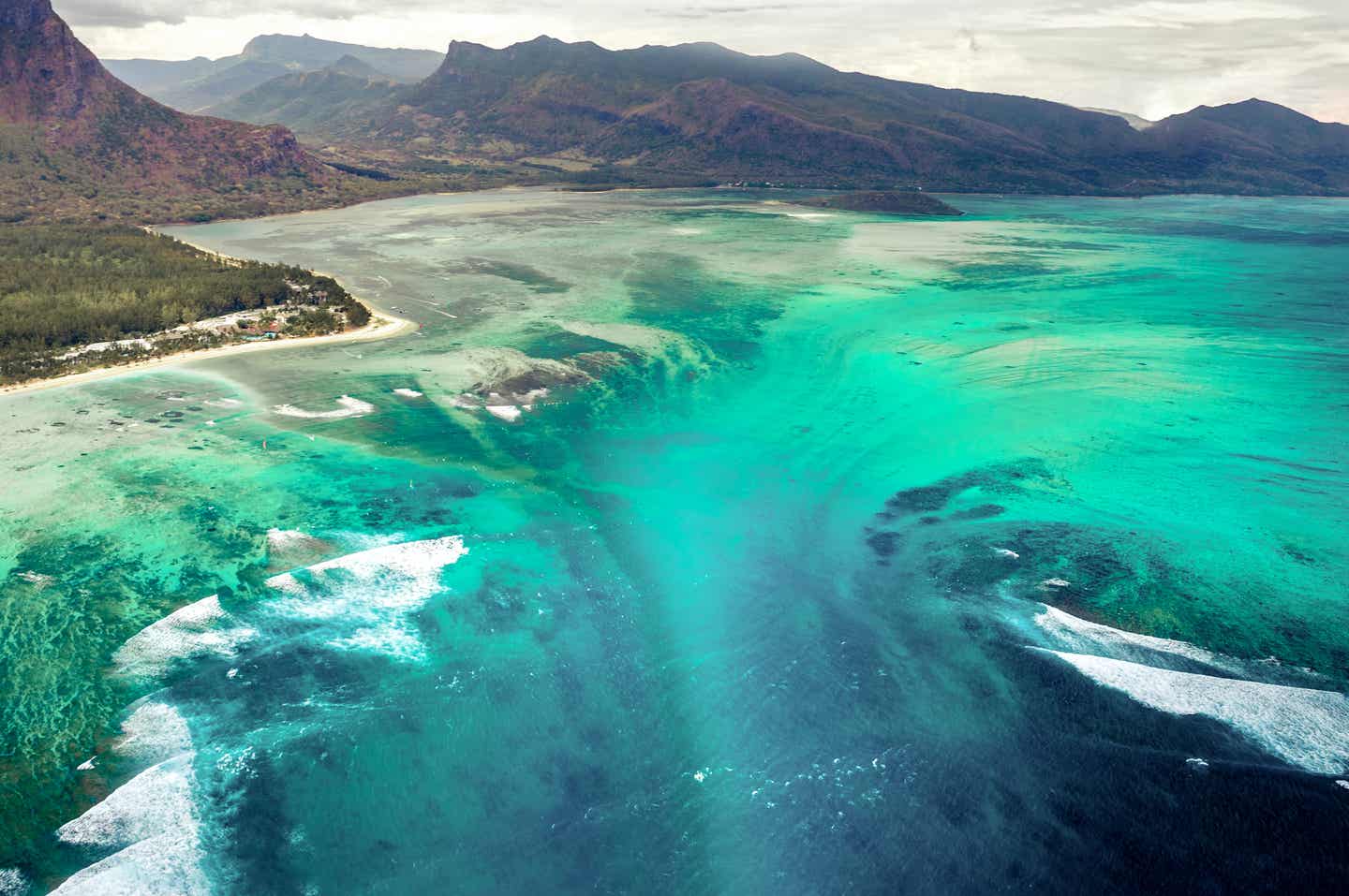 Der Unterwasser-Wasserfall vor der bergigen Küste von Mauritius, wie er in schönsten Blau-Grün-Tönen in die Tiefe stürzt