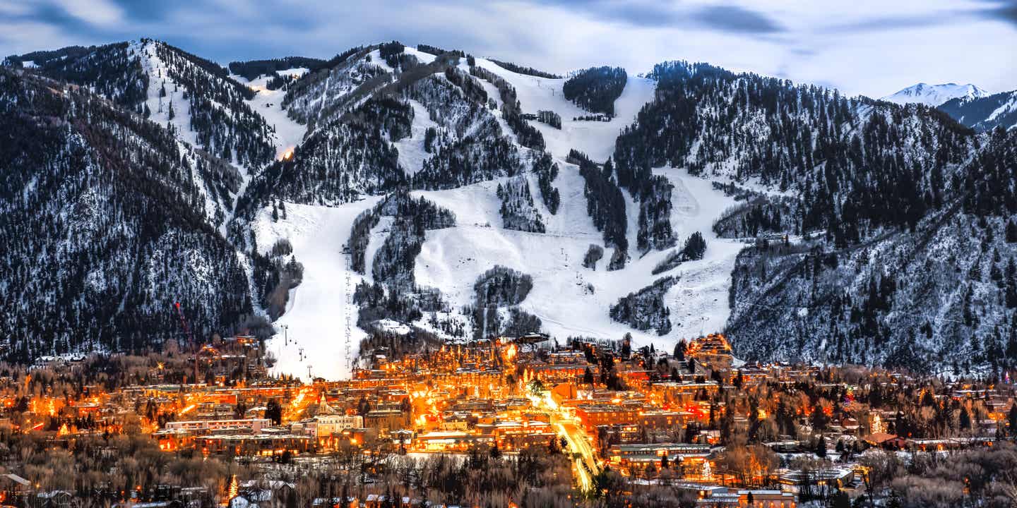Kleinstadt Aspen bei Nacht vor schneebedeckter Bergkulisse