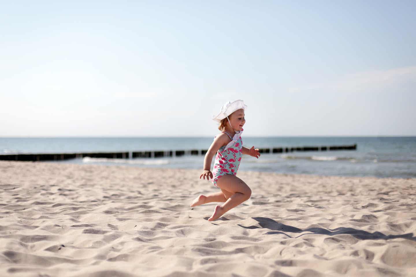 Kühlungsborn Urlaub mit DERTOUR. Kind im Bademantel läuft zwischen Strandkörben umher