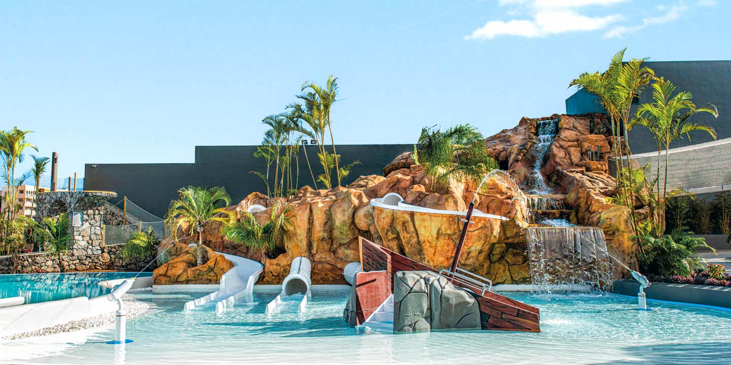 Blick auf einen Pool mit Wasserrutschen und künstlichen Felsen für Kids