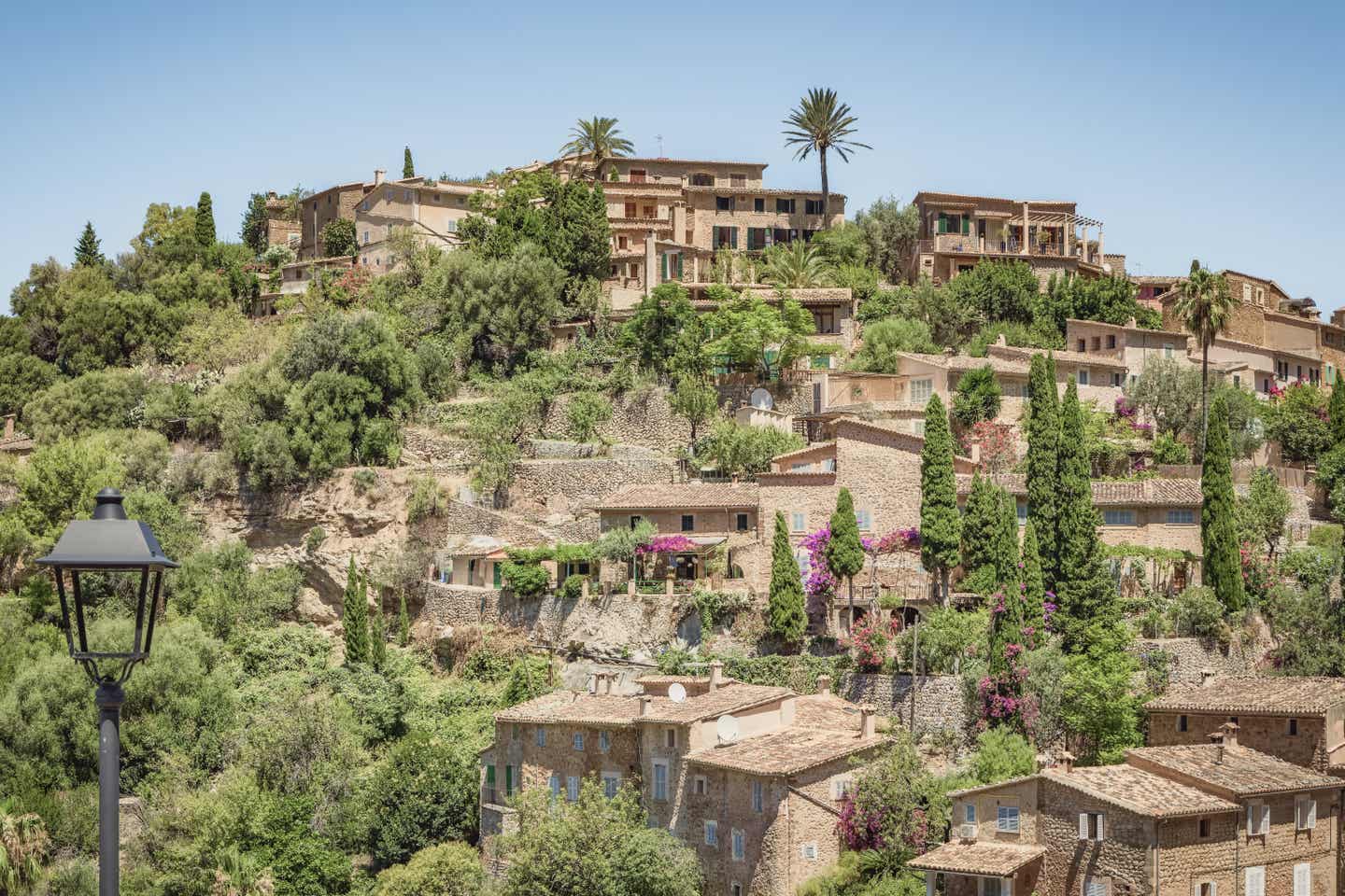 Blick auf das malerische Dorf Deià auf Mallorca, eine beliebte Mallorca-Sehenswürdigkeit, eingebettet in die Hänge der Serra de Tramuntana mit traditioneller Architektur und mediterraner Vegetation