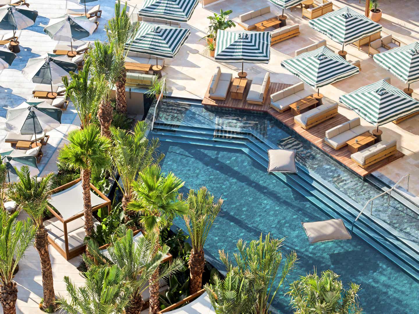 Poollandschaft des Daios Cove auf KReta Pool mit grünen Palmen und Sonnenliegen und Schirmen