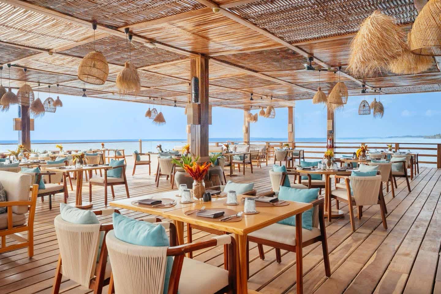 Genuss mit Meerblick – stilvoll speisen im Aldiana Club Zanzibar Kwanza Offenes Restaurant im Aldiana Club Zanzibar Kwanza mit Meerblick, Naturmaterialien und stilvoller Holzterrasse auf Sansibar