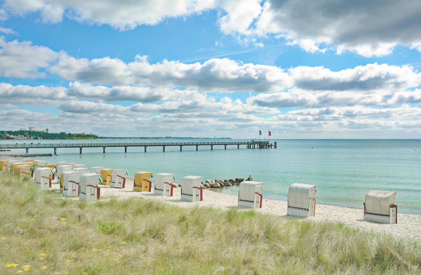 Strahlend blauer Himmel am Timmendorfer Strand mit grünem Gras und Strandkörben im Sand